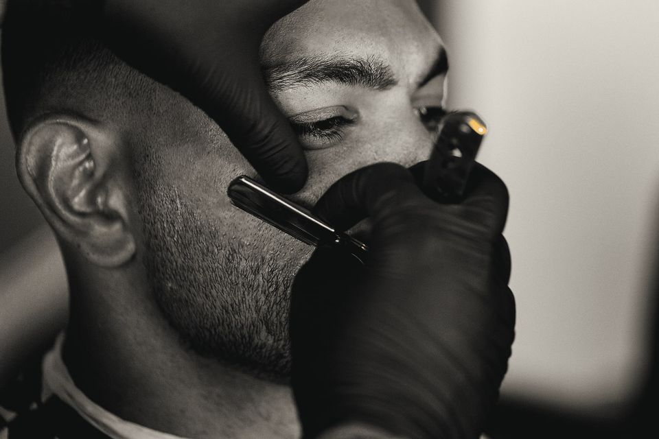 A straight razor lining up a beard along the cheek.