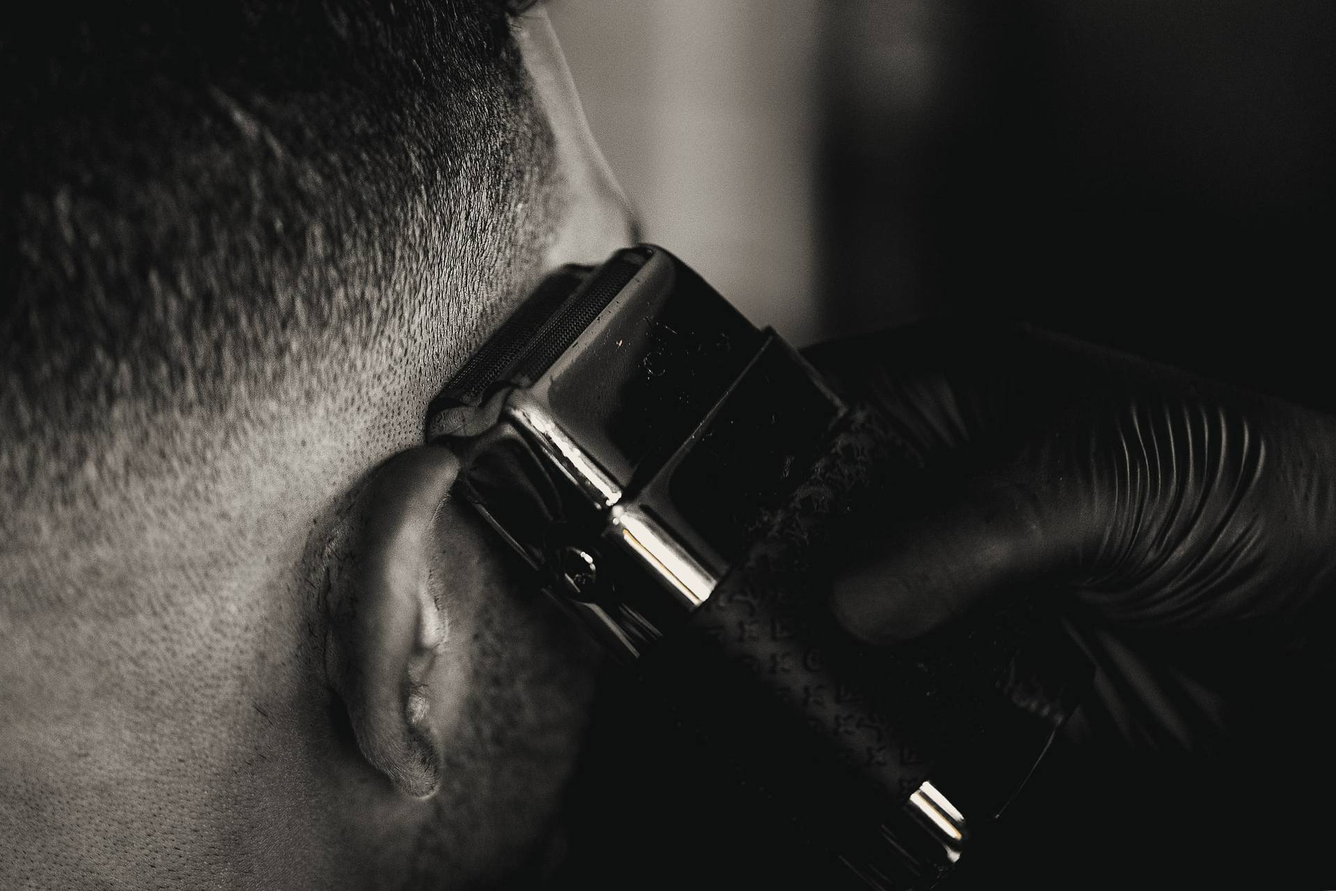 Close-up of a gold foil shaver finishing a skin fade above the ear.