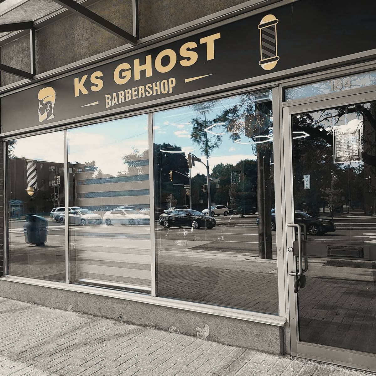 The KS Ghost Barbershop storefront on Wilson Avenue: a dark fascia with gold lettering, a barber pole and wide windows.