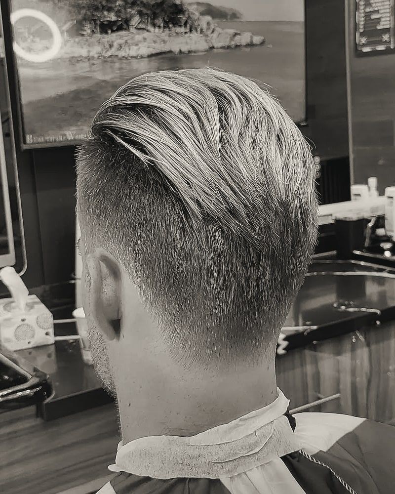 Back and side view of blond hair swept back over tapered sides.