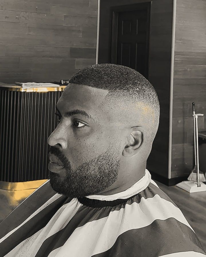 A short buzz cut blended into a skin fade, with a lined-up beard.