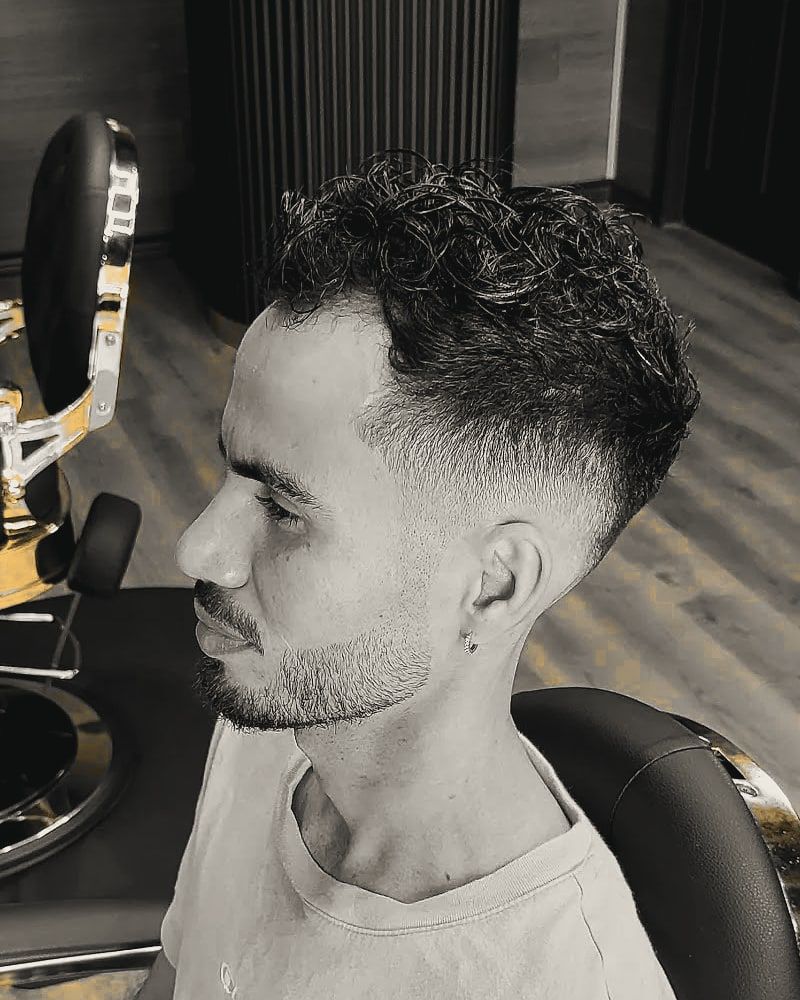 Curly hair on top over a skin fade on the sides.