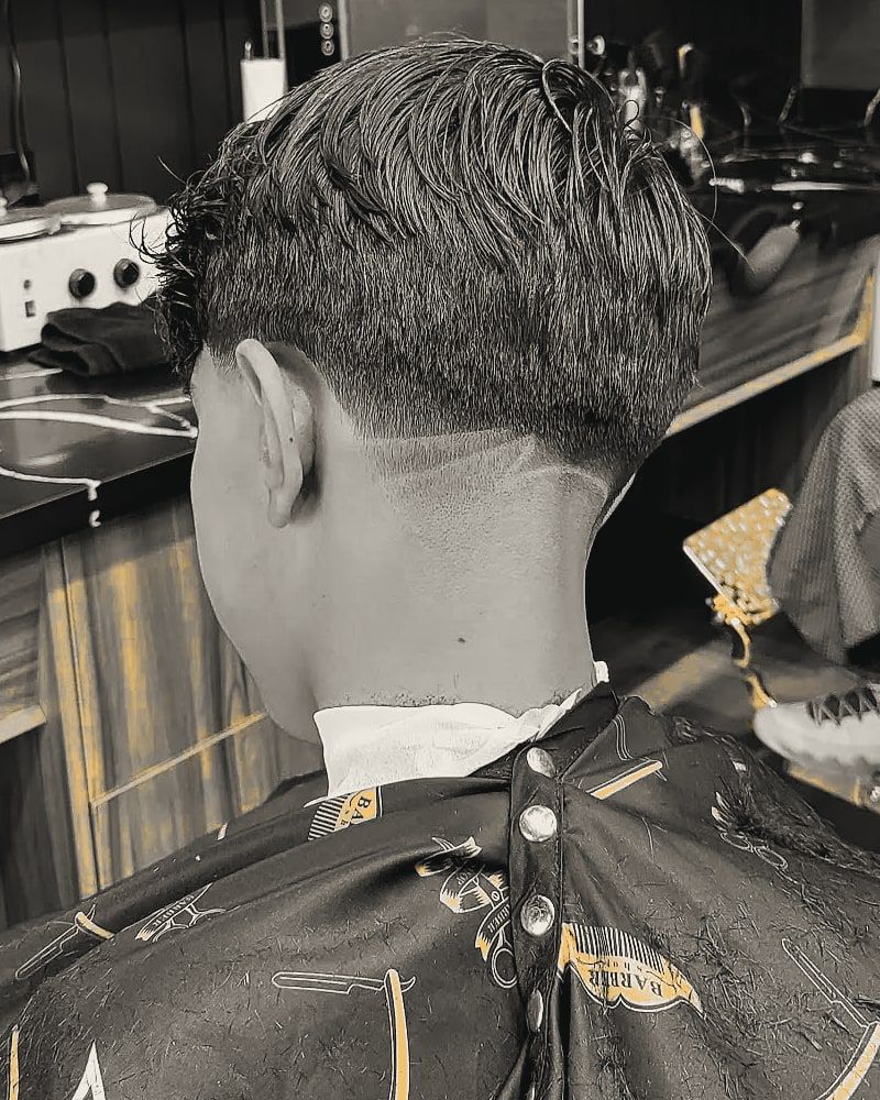 Back view of a textured haircut with a clean taper at the nape.